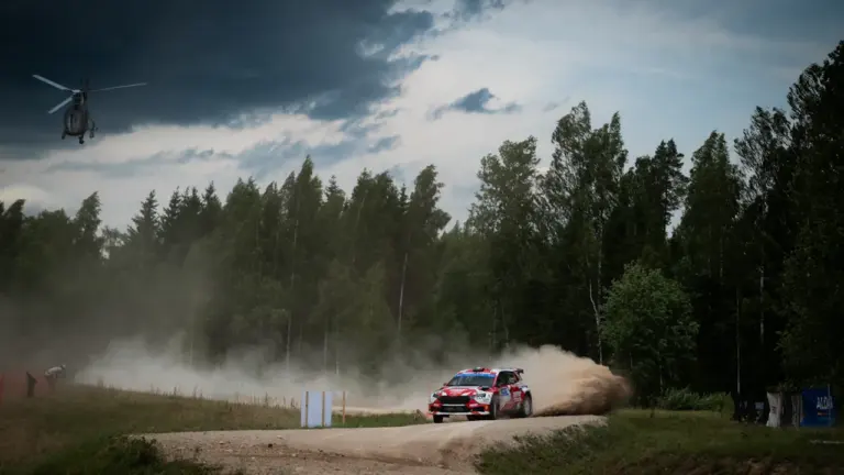 Ralliauto sõitmas tolmulisel kruusateel läbi Eesti loodusliku metsamaastiku suurel kiirusel