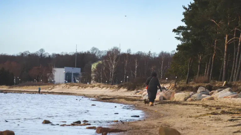 Inimene kõndimas mereäärsel rannal augusti lõpu jahedama ilmaga Eestis.