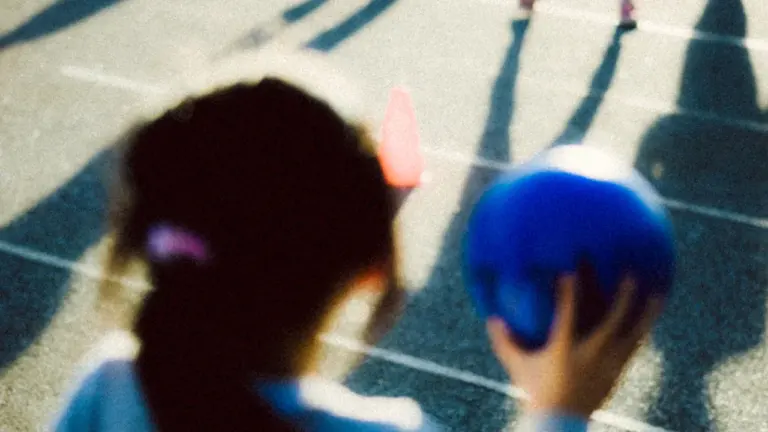 Tüdruk hoiab sinist palli treeningväljakul, valmistudes käsipallitreeninguks Valga kooli spordiplatsil.