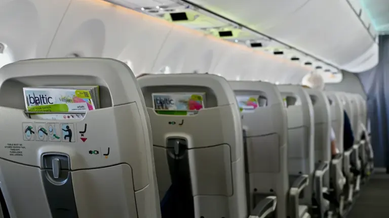 Air Balticu lennuki salong tühjade istmeridadega, kus on näha ettevõtte ajakirju istmetaskutes.